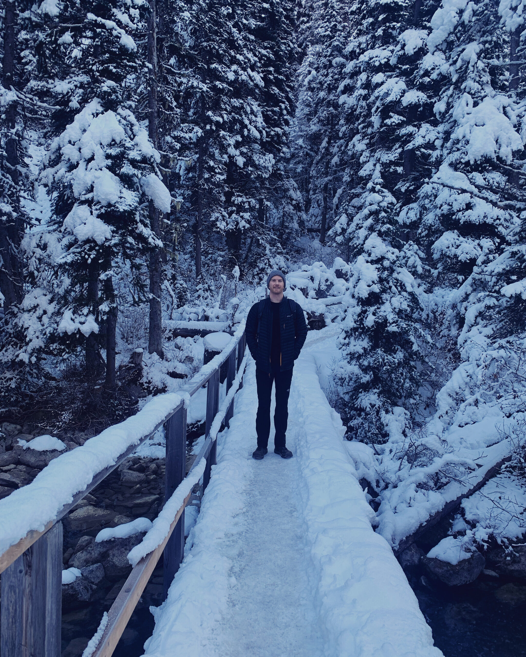 Man standing on snow covered bridge in snowy forest in British Columbia, Canada