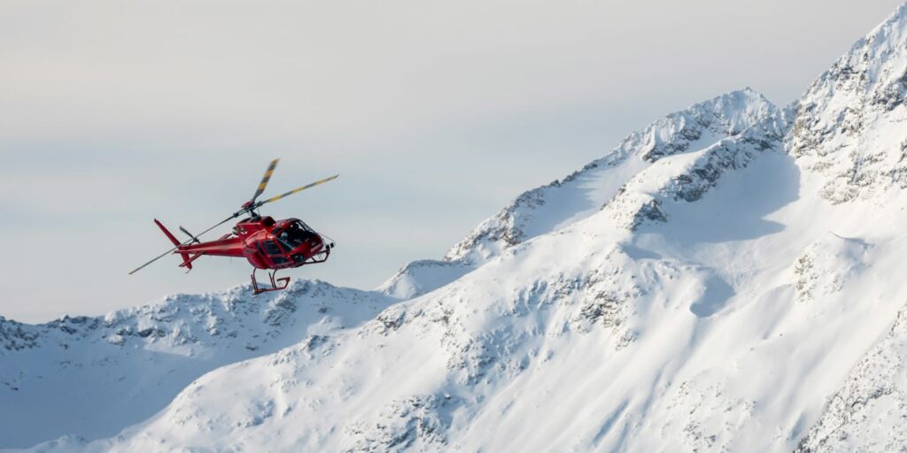 Helicopter flying through snowy mountain range near Whistler, Canada