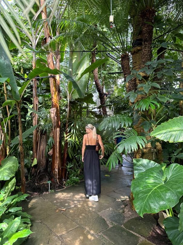 Woman standing amongst the gardens at the palm house in Copenhagen