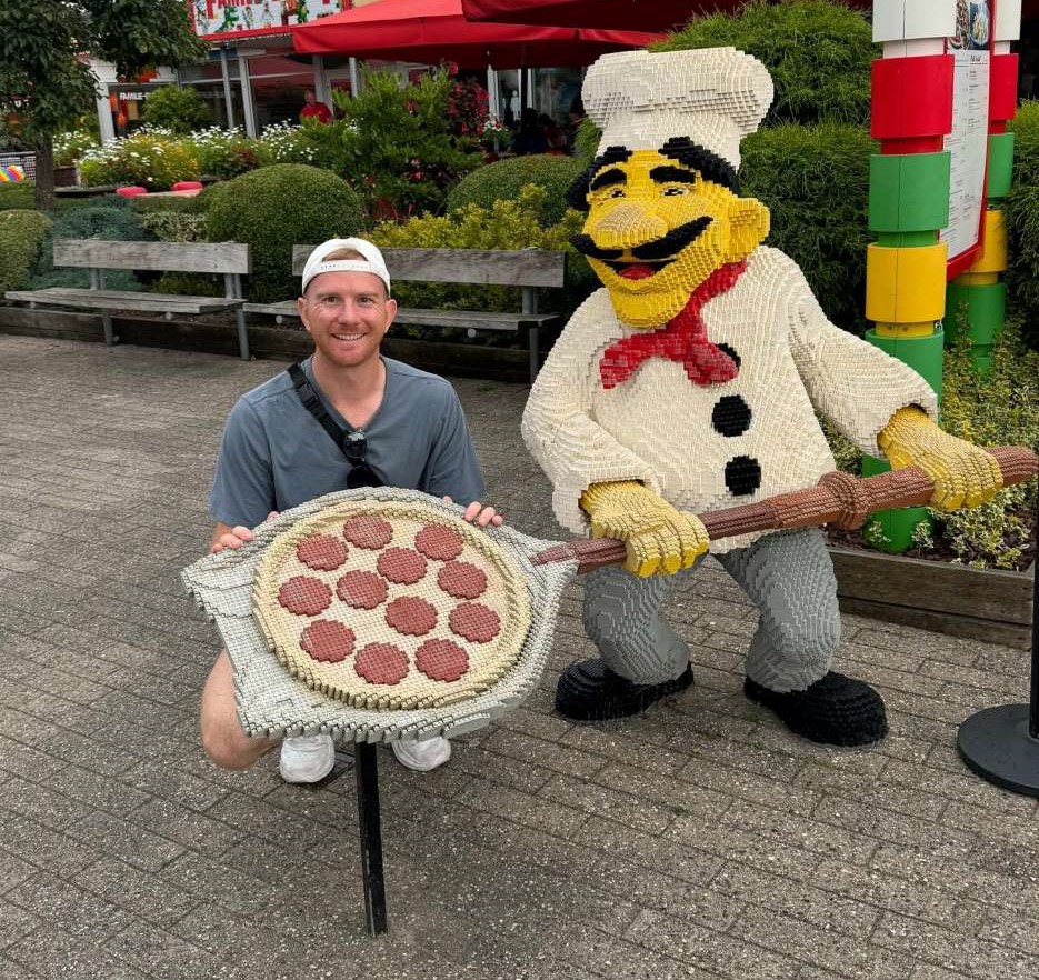 Man posing with Lego pizza chef statue model at Legoland Billund